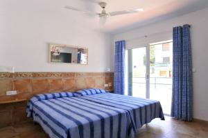 a bedroom with a blue and white striped bed and a window at Apartaments El Berganti en Canyelles Petites in Roses