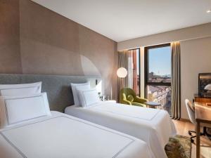 two beds in a hotel room with a window at Swissôtel Tbilisi in Tbilisi City