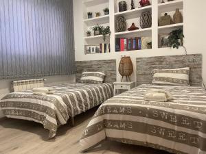 ein Schlafzimmer mit 2 Betten und einem Regal mit Büchern in der Unterkunft Encanto cuenca puerta al silencio in Cuenca