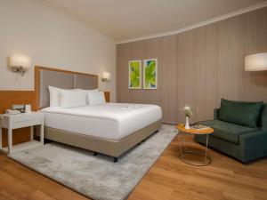 a bedroom with a bed and a green chair at Rixos Park Belek - The Land Of Legends Access in Belek