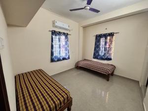 Una habitación con dos camas y un ventilador de techo. en Varaham PG - Pallikaranai, en Chennai