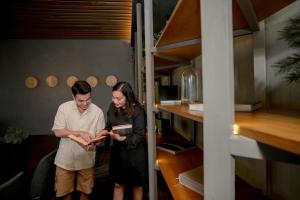 Un hombre y una mujer están de pie en una habitación mirando un libro. en Ceylonz Leisure Suites KLCC Bukit Bintang, en Kuala Lumpur