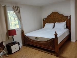 a bedroom with a wooden bed with white sheets and a window at Park Vill 202 in Pyeongtaek