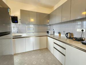 a kitchen with white cabinets and white appliances at Ultra Luxe 2BHK Candolim Service Apartment with River and Mangrove Views in Candolim