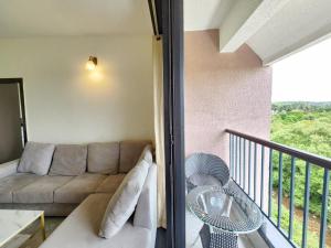 a living room with a couch and a balcony at Ultra Luxe 2BHK Candolim Service Apartment with River and Mangrove Views in Candolim