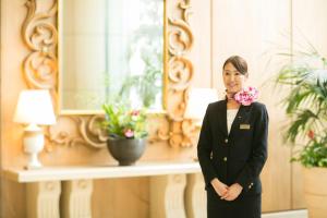 Eine Frau steht vor einem Spiegel in der Unterkunft Princess Garden Hotel in Nagoya