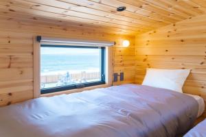 a bedroom with a bed and a window with the ocean at Lady Blue伊豆稲取 in Higashiizu +50 photos