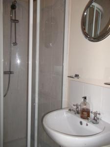 a bathroom with a sink and a shower with a mirror at Hathway House Accommodation in Redhill