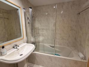 een badkamer met een douche, een wastafel en een bad bij Apartamentos Pilartxo Jaca 3000 in Jaca +17 foto's