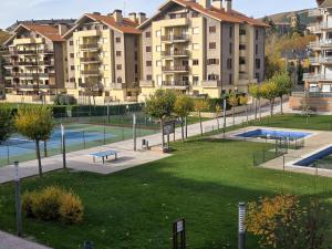 een appartementencomplex met een park met twee tennisbanen bij Apartamentos Pilartxo Jaca 3000 in Jaca