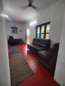 a living room with a leather couch and a red carpet at Cuba beach villa in Alleppey