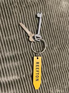 a key chain with a tag on top of a bed at Nourish Reefton & Wilsons Hotel in Reefton