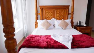 1 cama con sábanas blancas y manta roja en 3 Bhk Villa Ooty - Casa de Amor by EBR, en Ooty