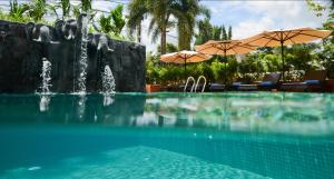 a swimming pool with a fountain and umbrellas at Royal Crown Hotel & Spa in Siem Reap