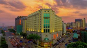 a large white building with cars parked in a city at Dongguan Jun Hao Hotel in Dongguan