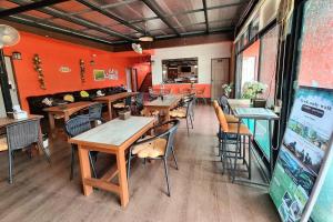 een restaurant met houten tafels en stoelen en oranje muren bij Chat House Chiang Rai in Chiang Rai