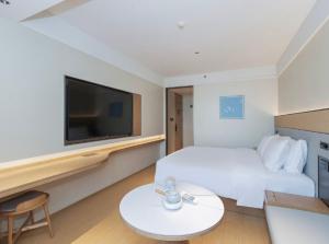 een hotelkamer met een wit bed en een televisie bij JI Hotel Beijing Xizhimen in Beijing