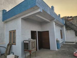 a white house with a blue roof with a fan at C-57, Nitin khandelwal in Jaipur