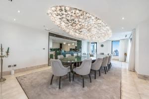 a dining room with a glass table and white chairs at FAM Living- Luxe Penthouse in JBR Marina - Panaromic Sea View in Dubai
