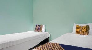 two beds sitting next to each other in a room at Hotel O Amazon Homestay Syariah 2 in Cibadak