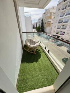 ein Balkon mit einer Bank und Gras auf dem Boden in der Unterkunft Résidence Jade in Sousse