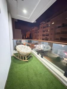 einen Balkon mit einem Tisch und einem grünen Teppich in der Unterkunft Résidence Jade in Sousse