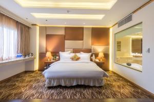 a bedroom with a large bed and a large mirror at Luxus Grand Hotel in Lahore