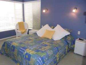 a bedroom with a bed and a yellow chair at A LAKEHOUSE ESCAPE - a Waterfront Reserve on shores of Lake Macquarie in Bonnells Bay