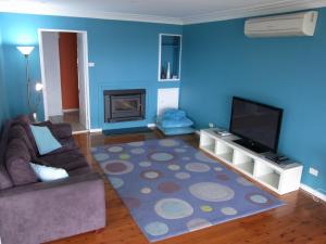 a blue living room with a couch and a television at A LAKEHOUSE ESCAPE - a Waterfront Reserve on shores of Lake Macquarie in Bonnells Bay