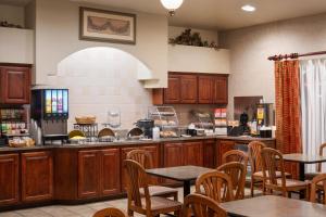 a kitchen with wooden cabinets and tables and chairs at Hawthorn Suites by Wyndham Napa Valley in Napa