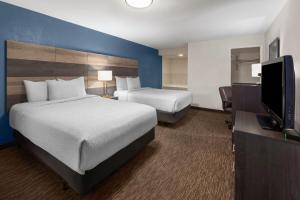 a hotel room with two beds and a flat screen tv at Baymont by Wyndham Downtown Detroit in Detroit