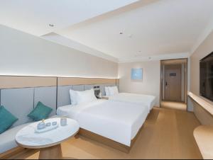 een hotelkamer met een groot wit bed en een tafel bij JI Hotel Beijing Xizhimen in Beijing