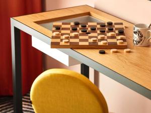 een schaakbord op een bureau met een gele stoel bij Mama Shelter Dijon in Dijon