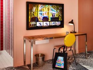 een bureau in een kamer met een televisie aan de muur bij Mama Shelter Dijon in Dijon