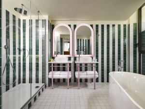 een badkamer met 2 wastafels, een bad en een spiegel bij Mama Shelter Dijon in Dijon