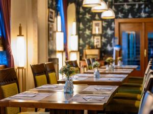 une rangée de tables dans un restaurant avec des fleurs dans l'établissement Mercure Szekesfehervar Magyar Kiraly, à Székesfehérvár