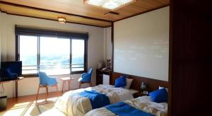 a bedroom with two beds and a large window at Ikadasou Sanjou in Matoya