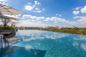 a large swimming pool with an umbrella next to a building at Crowne Plaza Vientiane by IHG in Vientiane