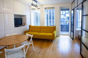 Una sala de estar con un sofá amarillo y una mesa. en Black Pearl Apartament Centrum, en Szczecin