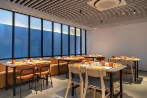 a restaurant with tables and chairs and large windows at TMG Hotel Tebet, Marclan Collection in Jakarta