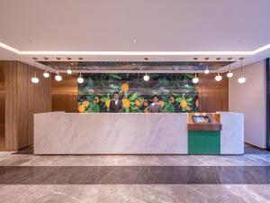 a lobby with a reception desk with a painting of fruit at Orange Hotel Beijing South Railway Station South Square in Beijing
