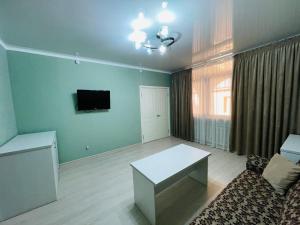 a living room with a couch and a table and a tv at The green regency in Toshkent-Passajir Bekati