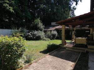 a backyard with a brick patio and a wooden pergola at L'escapade Beaujolaise in La Chapelle-de-Guinchay