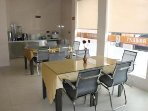 a dining room with a table and chairs and a kitchen at 7 Days Premium Haiyan New Bridge South Road Branch in Haiyan