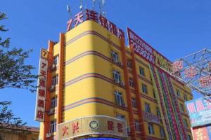 a yellow building with signs on the side of it at 7 Days Inn Hami Baofeng Market in Qumul