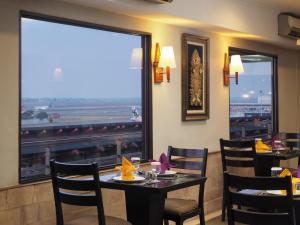 a restaurant with tables and chairs and a large window at Jakarta Airport Hotel in Rawabagol