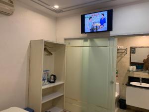 Un baño con un televisor en la pared encima de la ducha. en Maison d'Hanoi Hotel, en Hanói