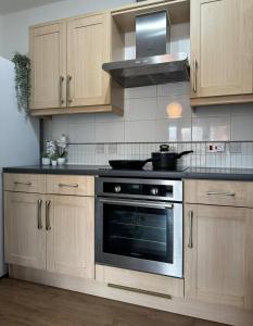 eine Küche mit Holzschränken und einem Herd mit Backofen in der Unterkunft City Centre Apartment - Free Parking - Sleeps 4 in Exeter