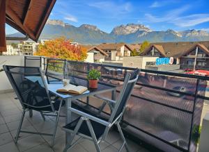 a table and chairs on a balcony with mountains at Au cœur de St Jorioz, spacieux appartement avec terrasse et vue montagne. in Saint-Jorioz