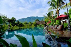 a pool in a resort with mountains in the background at San Signature - Suối Ngọc Retreat in Tien Xuan